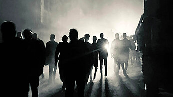 Blick auf eine nächtliche Straße mit mehreren Personen im Gegenlicht