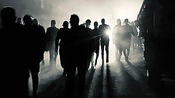 Blick auf eine nächtliche Straße mit mehreren Personen im Gegenlicht