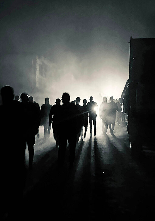 In einer gespenstischen Szenere irren im Dunkeln Menschen durch eine Straße