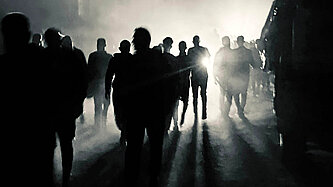 Blick auf eine nächtliche Straße mit mehreren Personen im Gegenlicht