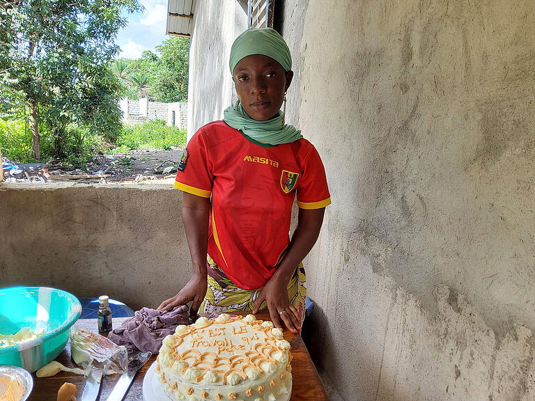Eine junge Frau steht vor einer Torte, die sie stolz präsentiert