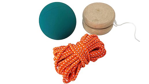 Grüner Flummi, aufgerollter orangefarbener Gummitwist und Jojo aus Holz, natur