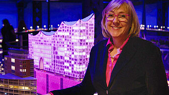 Kathrin Hartkopf steht neben der Elbphilharmonie im Miniaturwunderland, die pink angestrahlt wird.