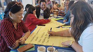 Erwachsene Teilnehmer:innen arbeiten gemeinsam bei einem Workshop zur Prävention von Kinderhandel auf den Philippinen – organisiert mithilfe von Plan International.