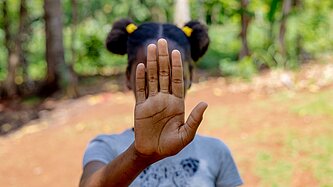 Mädchen hält Hand vor Gesicht 