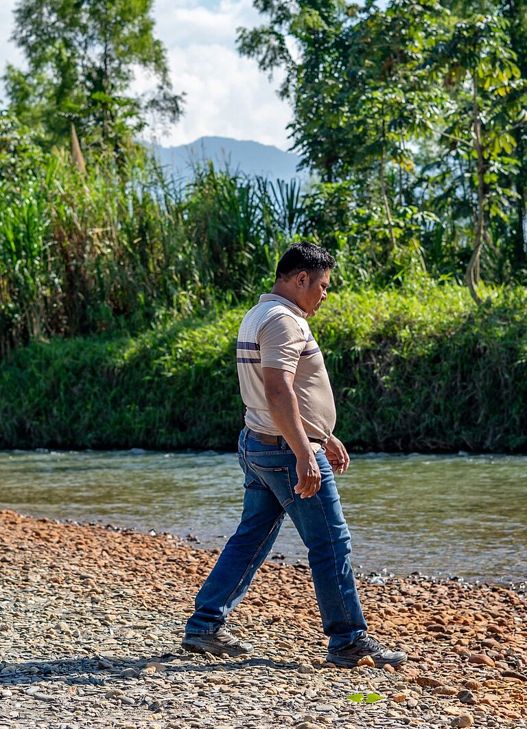 Aníbal steht am Fluss neben seines Hauses 