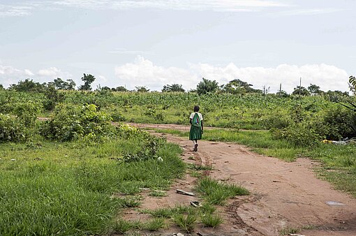 Ein Mädchen läuft durch grüne Felder in Tansania