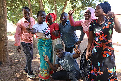 Menschen posieren ausgelassen unter einigen Bäumen