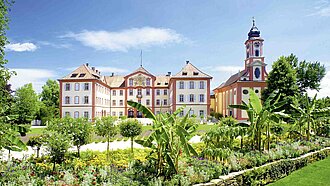 Blick auf ein prachtvolles Schloss in einem üppig grünen Garten