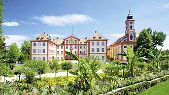 Blick auf ein prachtvolles Schloss in einem üppig grünen Garten