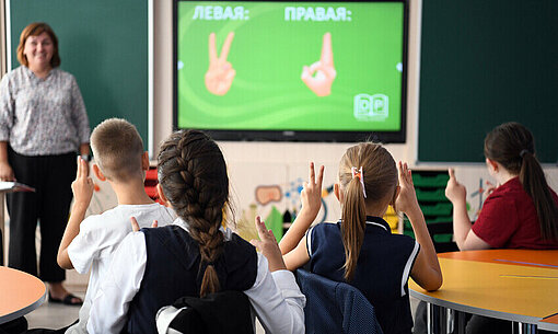 Kinder sitzen in einem Klassenzimmer und beteiligen sich am Unterricht