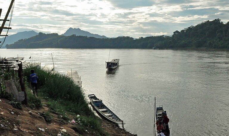 Menschen und Fähren am Mekong