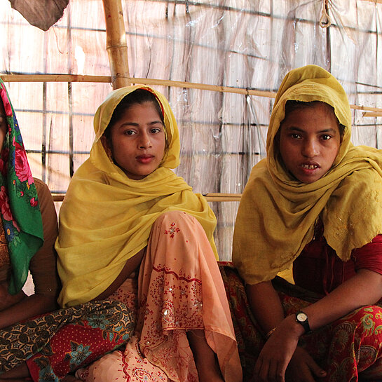 Vier Rohingya Mädchen sitzen auf dem Boden.