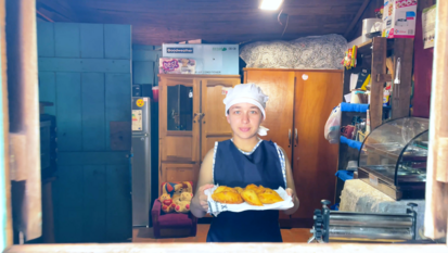 Eine junge Frau hält ein Blech mit Backwaren in der Hand