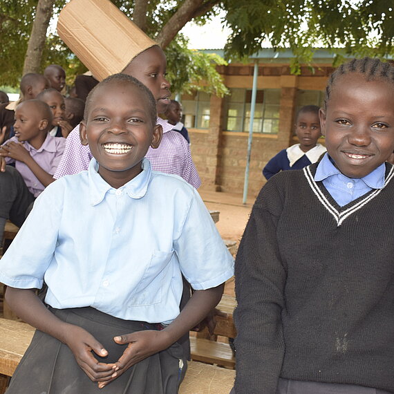 Zwei Jungen sitzen auf einer Schulbank und lächeln