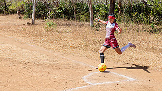 Eine junge Frau im roten Fußballtrikot holt aus zum Eckschuss.