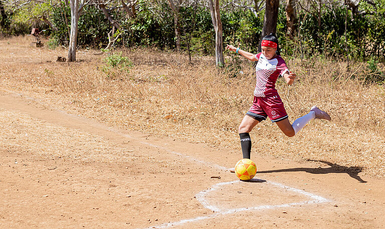 Eine junge Frau im roten Fußballtrikot holt aus zum Eckschuss.