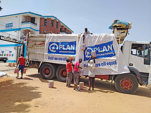 Ein LKW mit Plan International-Logo wird mit Waren beladen