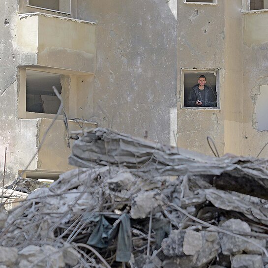 Ein Mann schaut aus dem Fenster eines zertrümmerten Hauses in Libanon