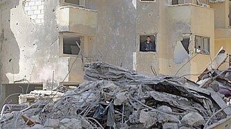Ein Mann schaut aus dem Fenster eines zertrümmerten Hauses in Libanon