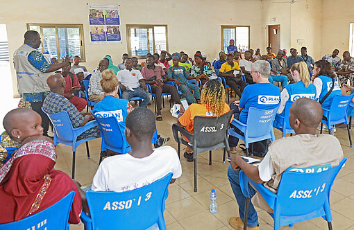 Mehrere Frauen und Männer sitzen in einer Halle und diskutieren angeregt