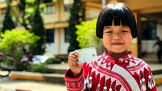 Die achtjährige Sirilak zeigt stolz ihren Ausweis, den sie nach ihrer Registrierung erhalten hat.