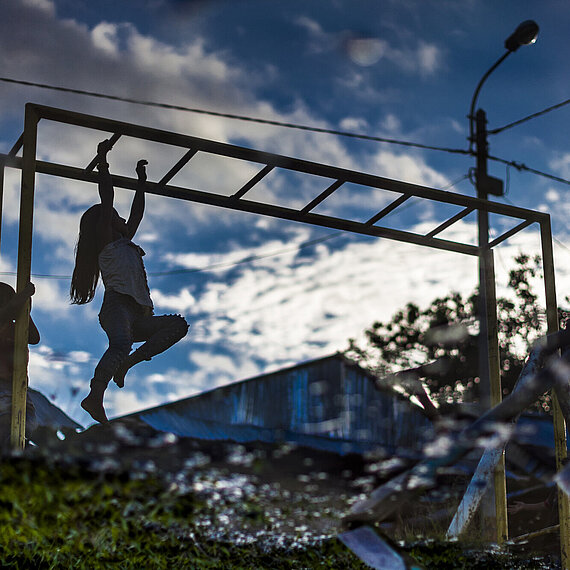 Kinder spielen auf einem Klettergerüst vor dramatischem Himmel – Symbolbild für Zukunft für Kinder