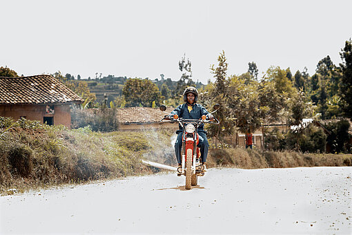 Clarisse fährt mit dem Motorrad durch ihre Gemeinde in Ruanda