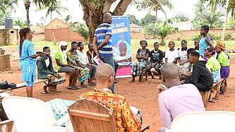 Junge Menschen mit Lehrenden sitzen draußen im Kreis und nehmen an einer Schulung teil