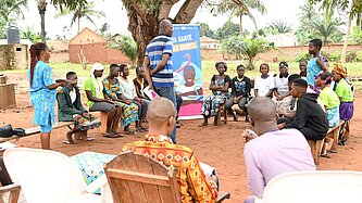 Junge Menschen mit Lehrenden sitzen draußen im Kreis und nehmen an einer Schulung teil