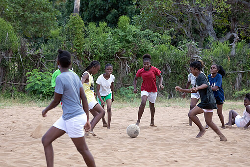 Mädchen spielen Fußball im Sand