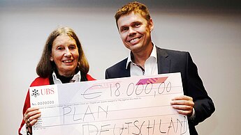 Carsten Koerl, CEO und Gründer von Sportradar, übergibt Dorothea Licht von der Aktionsgruppe München den Spendenscheck in Höhe von 18.000 Euro.