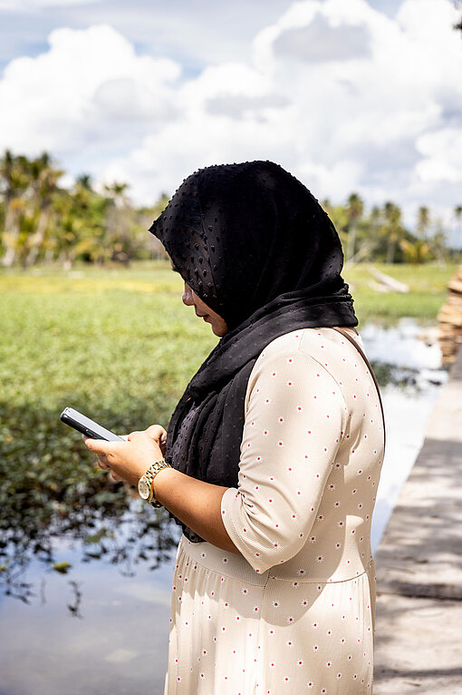 Farhana schaut auf ihr Smartphone.