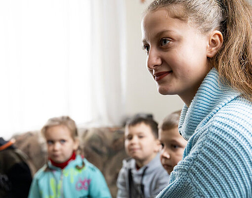 Veronica zusammen mit vier Pflegekindern der Familie auf dem Sofa sitzend