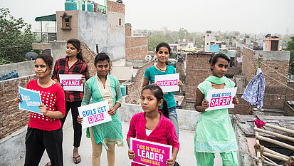 Eine kleine Gruppe Mädchen hält Schilder in ihren Händen, auf denen Forderungen für die Gleichstellung der Geschlechter zu lesen sind.