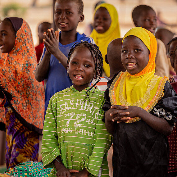 Zwei Kinder stehen nebeneinander in einer Gruppe anderer Kinder