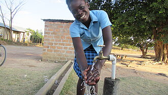 Eine junge Frau wäscht sich die Hände an einer Handwaschstation.