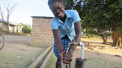 Eine junge Frau wäscht sich die Hände an einer Handwaschstation.
