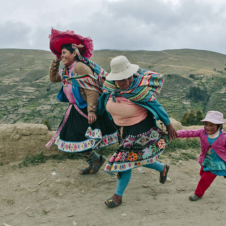 Frauen laufen lachend über die Anden-Hochebene
