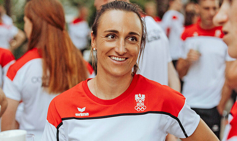 Eine Frau mit Sporttrikot steht zusammen mit anderen Personen in Trikots und lächelt in die Kamera