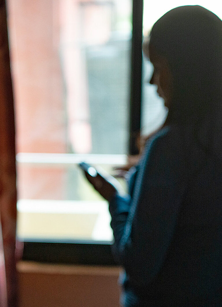 Eine junge Frau steht in einer Fensterflucht