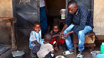 Ein Vater verteilt Essen an drei kleine Kinder