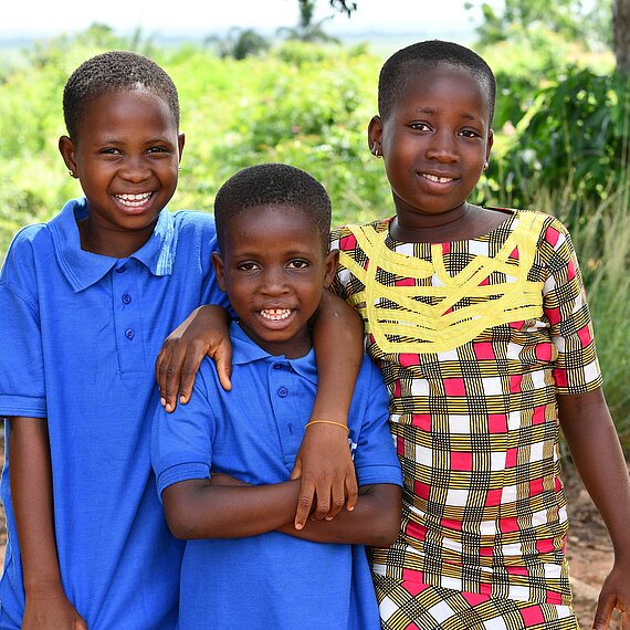 Drei Kinder lächeln Arm in Arm