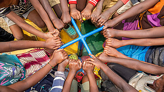 Viele Arme von Kindern ergreifen eine Haltestange in der Mitte eines Karussells