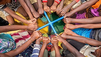 Viele Arme von Kindern ergreifen eine Haltestange in der Mitte eines Karussells