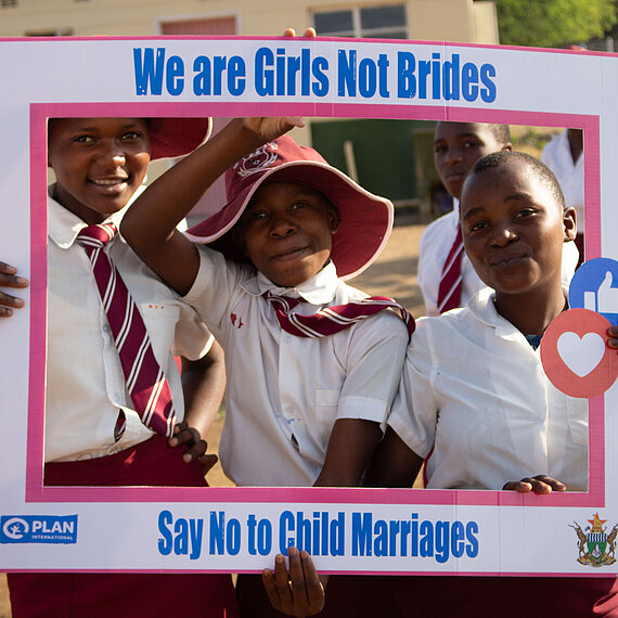 Schulmädchen in Uniform halten Schild mit der Aufschrift „We are Girls Not Brides – Say No to Child Marriages“ und setzen sich gegen Kinderheirat ein