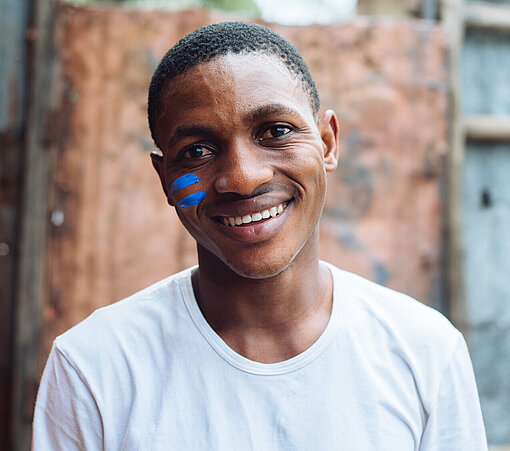 Portrait von Anthony mit zwei blauen Streifen auf der Wange.