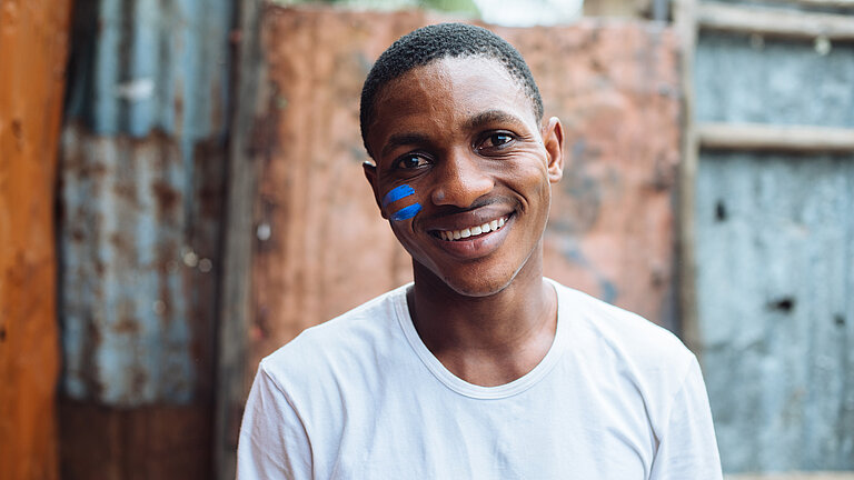 Portrait von Anthony mit zwei blauen Streifen auf der Wange.