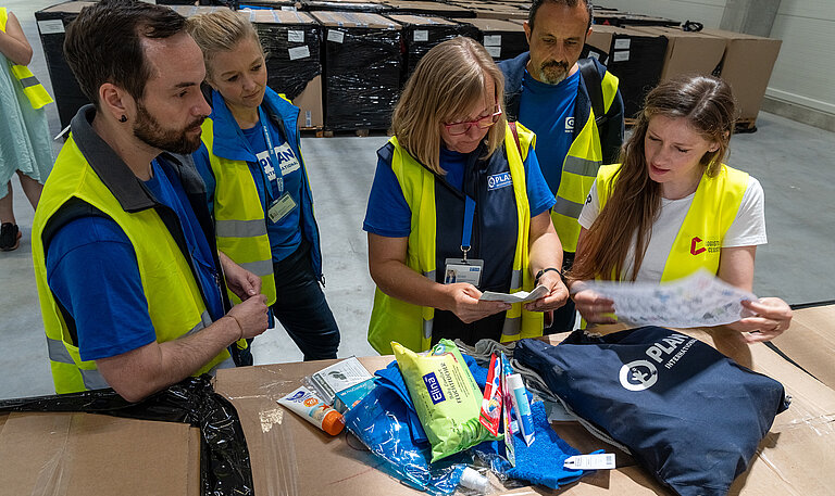 Mitarbeitende von Plan International begutachten ein Dignity Kit