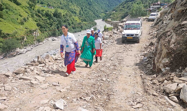Auf einer Straße voller Geröll laufen mehrere Personen
